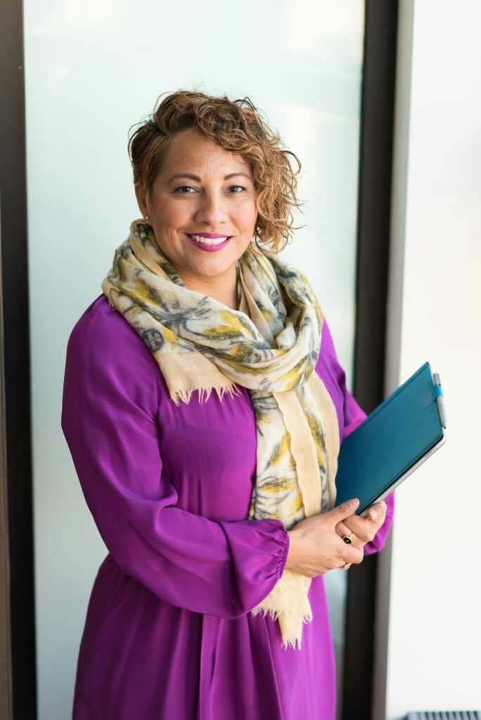 Tarifvergleich und Service Smiling woman in a purple dress and scarf holding a tablet indoors.